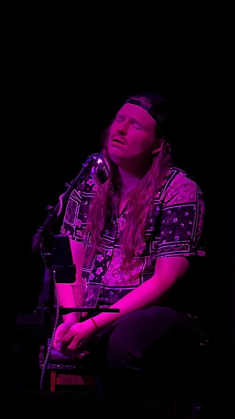 Ben Becker singing, eyes closed, under pink light